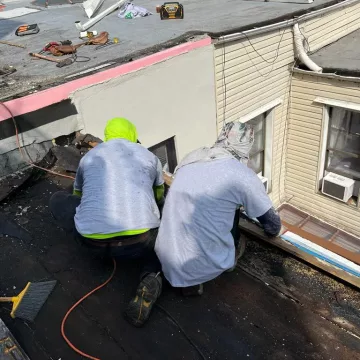 two people removing side waste of the previous roof.
