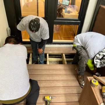 three people repairing roof inside the home of a single room